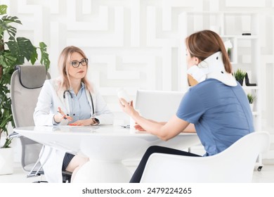 Female doctor traumatologist-orthopedist explaining to her patient with serious neck injury in neck brace about importance of cervical collar for healthy cure - Powered by Shutterstock