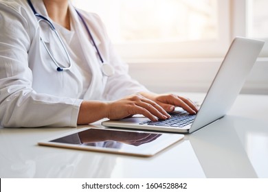 Female Doctor Typing On Her Laptop Computer In Medical Office