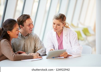 Female Doctor Using Digital Tablet Talking With Patients - Powered by Shutterstock