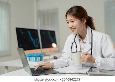 Female doctor is using a laptop and drinking coffee at her desk in a modern medical laboratory, with a dna double helix displayed on the computer screens behind her - Powered by Shutterstock