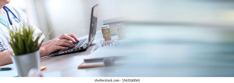 Female Doctor Using Laptop In Medical Office; Panoramic Banner