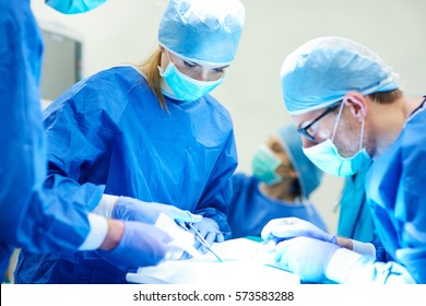 Female Doctor Using Medical Scissors Over Surgery