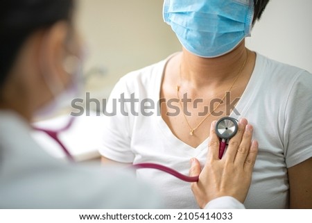 Female doctor using stethoscope exam Asian female patient for physical examine pneumonia lung sound checkup in hospital. Coronavirus, covid-19, medical and healthcare concept