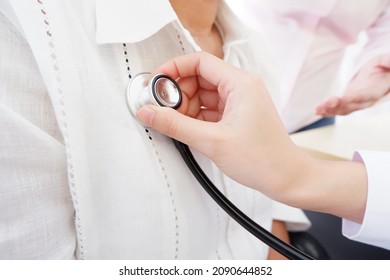 A female doctor using a stethoscope to listen to the heart of an elderly woman. to perform treatment