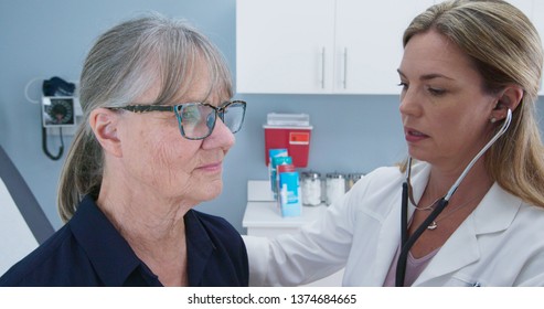 Female Doctor Using Stethoscope On Senior Woman Patient. Older Woman Visiting Her Primary Care Physician For A Regular Check Up