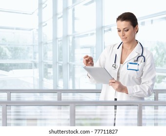 Female doctor using tablet computer in hospital lobby, smiling.? - Powered by Shutterstock