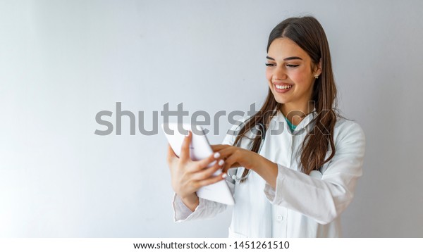 Female doctor\
using tablet computer in hospital lobby, smiling. Woman doctor\
using tablet computer while standing straight in hospital. Close-up\
of a female doctor using tablet\
PC