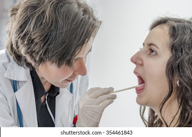 Female Doctor Using A Tongue Depressor With Girl Patient