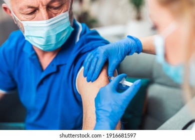 Female doctor vaccinating senior male patient at home. Coronavirus, Covid-19 concept. - Powered by Shutterstock