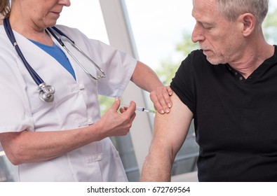 Female doctor vaccinating a senior man