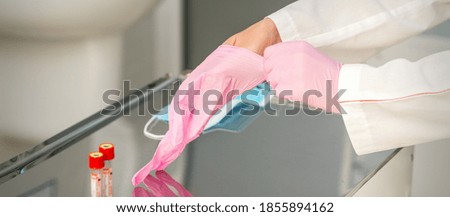 Female doctor wearing rubber protective gloves on her hands in the lab