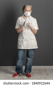 Female Doctor Wearing White Coat And Jeans Full Length. Mature Woman In Protective Mask Working With Digital Device.