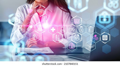 Female Doctor Wearing White Suit Is Sitting And Touching Chin. Digital Interface With Icons Of Dna, Syringe, Pills, Mask, Heart, Thermometer In Foreground. Concept Of Heath Care And Diagnostics