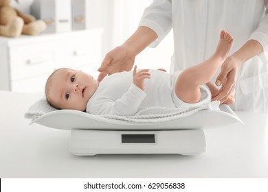 Female Doctor Weighting Cute Baby In Clinic