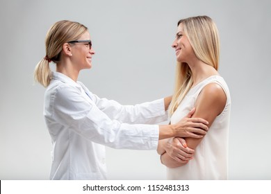 Female Doctor In A White Lab Coat Embracing A Woman Patient With A Quiet Smile Of Satisfaction And Pleasure At A Good Outcome To A Medical Problem