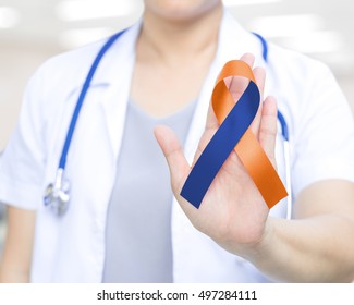 Female Doctor In White Uniform With Orange And Navy Blue  Ribbon Awareness In Hand For Human Rights For Family Caregivers Awareness. National Family Caregiver Month And Day.