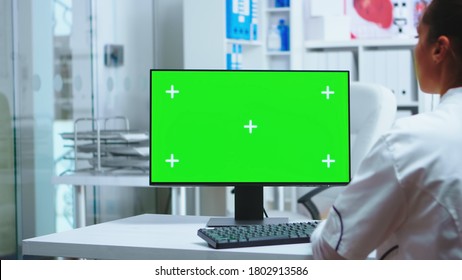 Female Doctor Working On Computer With Green Screen In Private Clinic Cabinet. Assistant In Uniform. Medic In White Coat Working On Monitor With Chroma Key In Clinic Cabinet To Check Patient Diagnose.