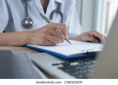 Female Doctor Working On Laptop Computer And Writing Patient Information In Medical Office In Hospital, Closeup. Medical Student Recording Health Report On Case Study