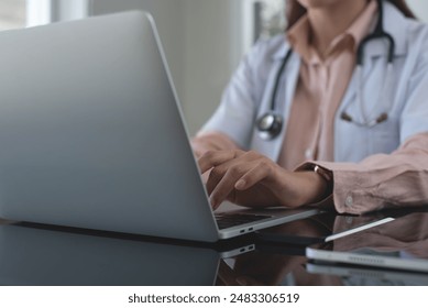 Female doctor working on laptop computer at doctor's office. writing prescripstion, recording patient's information, healthcare and medicine concept - Powered by Shutterstock