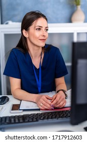 Female Doctor Working On Medical Expertise While Sitting At Desk In Front Of Computer.