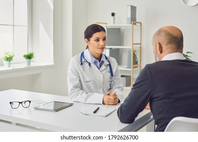 Female Doctor Writing Medication Order For Senior Patient In Clinic. Elderly Man On Visit To His Healthcare Provider