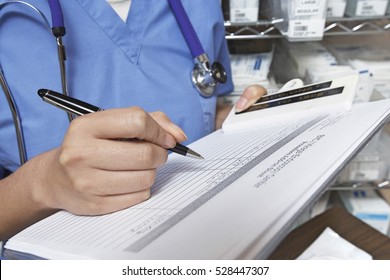 Female Doctor Writing In Patient Chart, Mid Section