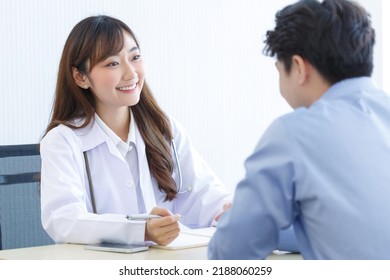 Female doctor and young male patient while consult and 
explain. Doctor and patient sitting together at table in examination room. - Powered by Shutterstock