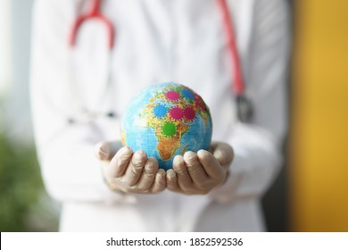 Female Doctor's Hands In Gloves Hold Globe. Disease Spread Around The World Concept