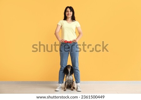 Female dog handler training pet on yellow background