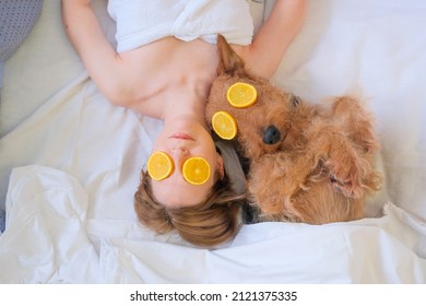 Female And Dog Laying In Bed With Orange Face Mask Having Spa Day