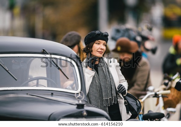 Female dressed in vintage clothes posing near\
retro car during a retro parade. Retro Cruise or Tweed run. October\
08 2016, Kyiv (Kiev),\
Ukraine.