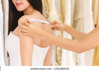 Female Dressmaker Measuring Woman's Back For Wedding Dress.