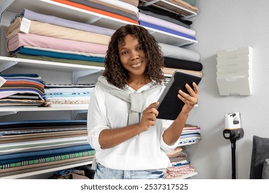 Female dressmaker in retail store choosing fabric using tablet to check stock place orders online - Powered by Shutterstock