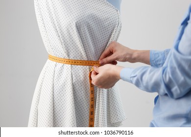 Female Dressmaker Working On New Model Tailoring Dress On Mannequin In Studio.