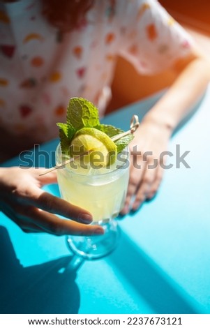 female drink yellow alcohol cocktail with lime, mint, ginger, honey in bar