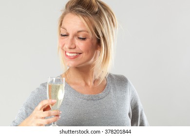 Female Drinker - Chic Beautiful Young Blond Woman Enjoying Drinking A Flute Of Bubbly Wine To Celebrate Her Success At Party, Gray Background
