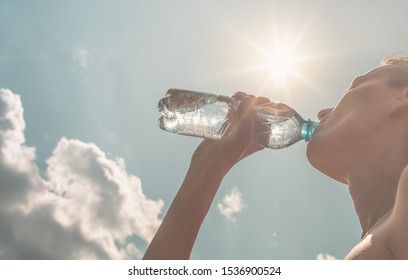 Female Drinking Water Outdoors On Hot Day.. 