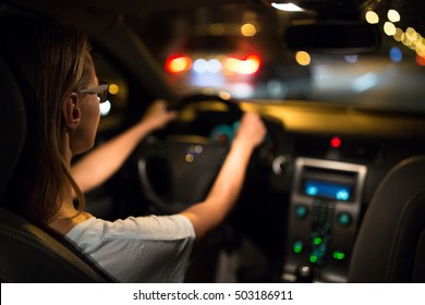 Female drive driving a car at night (shallow DOF; colour toned image)