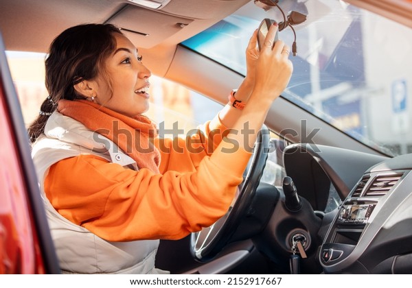 Female driver adjusts the rearview mirror, for\
safe and comfortable\
driving