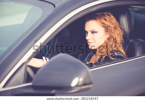 Female driver, driving a new black car. Hands on\
the steering wheel.\
