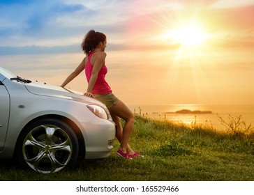 Female driver enjoying freedom and beautiful sunshine over the sea after driving to coast in summer vacation travel. Woman relaxing and taking a break to enjoy the scenery.