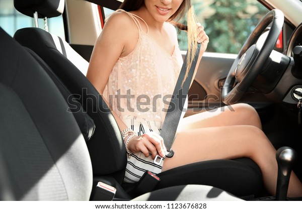 Female driver\
fastening safety belt in\
car