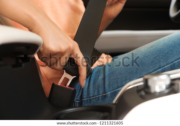 Female\
driver fastening safety belt in car,\
closeup