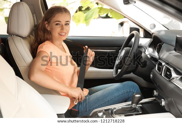 Female driver\
fastening safety belt in\
car