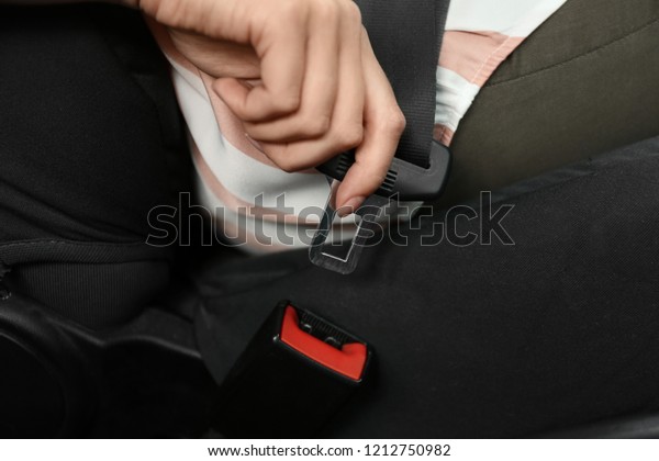 Female\
driver fastening safety belt in car,\
closeup