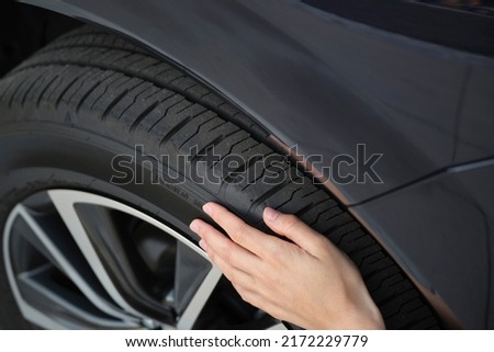 Female driver hands inspecting wheel tire of her new car. Vehicle safety concept