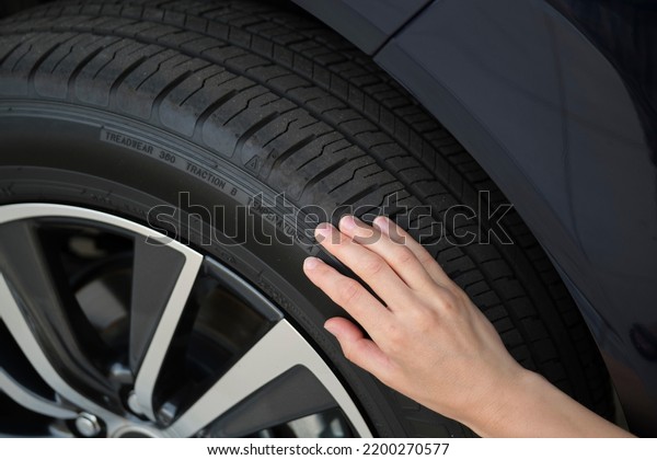 Female driver hands inspecting wheel tire of her\
new car. Vehicle safety\
concept