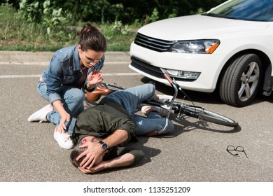 Female Driver Helping Male Biker After Car Accident On Road