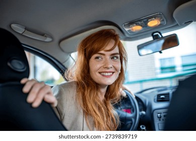 Female driver looking back while reversing a car in a city environment. Concept for vehicle safety, parking assistance, driver education, and automotive insurance protection.