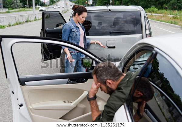 female\
driver looking at cars after car accident on\
road